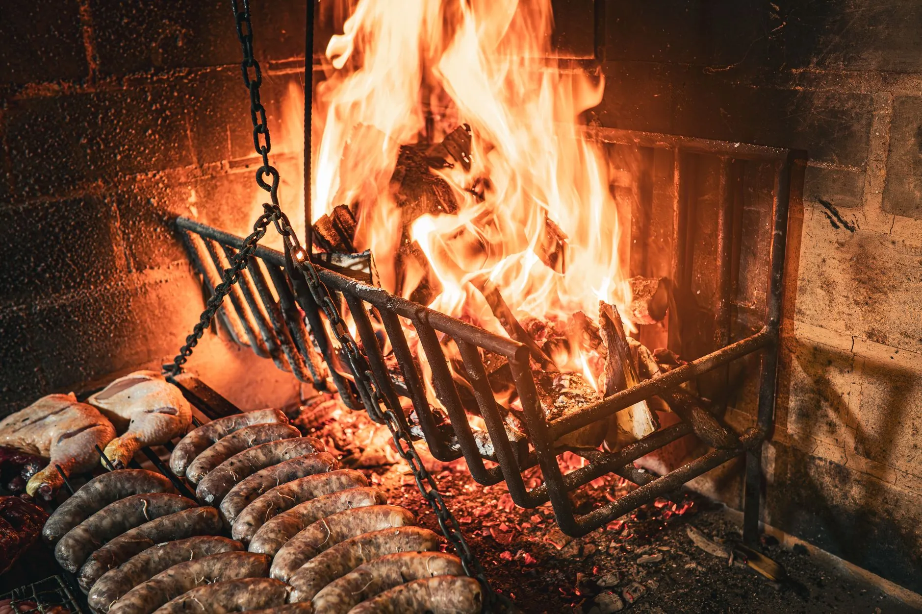 Parrilla encendida con brasas y leña de quebracho
